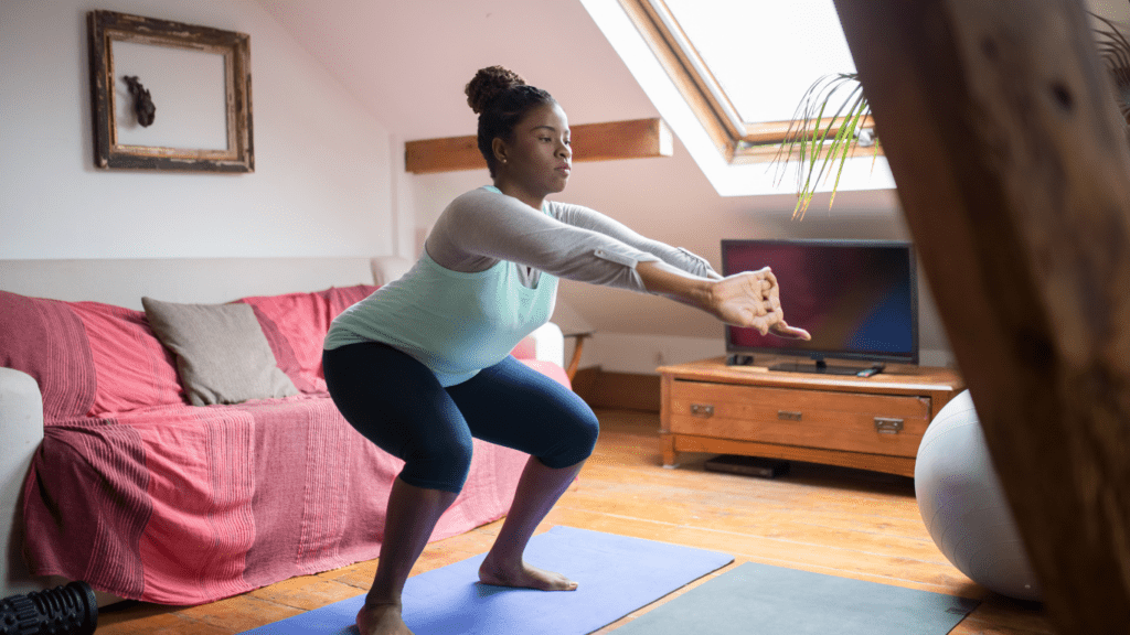 A person doing squats on a mat in a gym