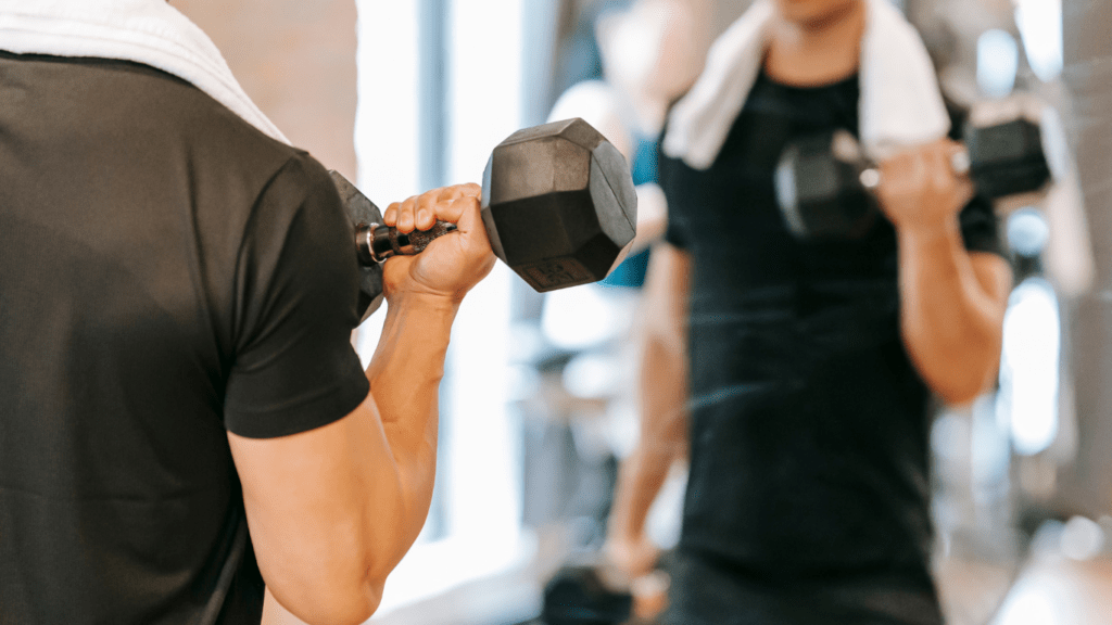 A person holding two dumbbells in a gym