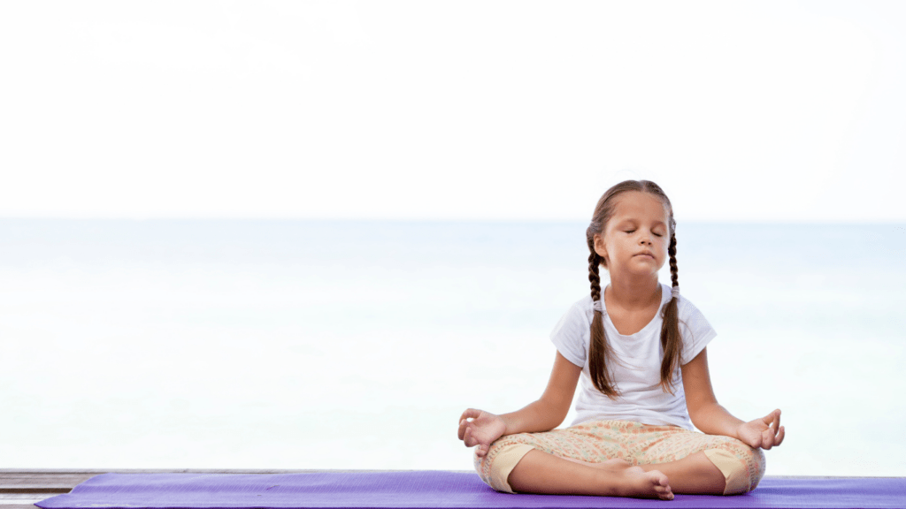 a person meditating on a yoga mat in front of the ocean