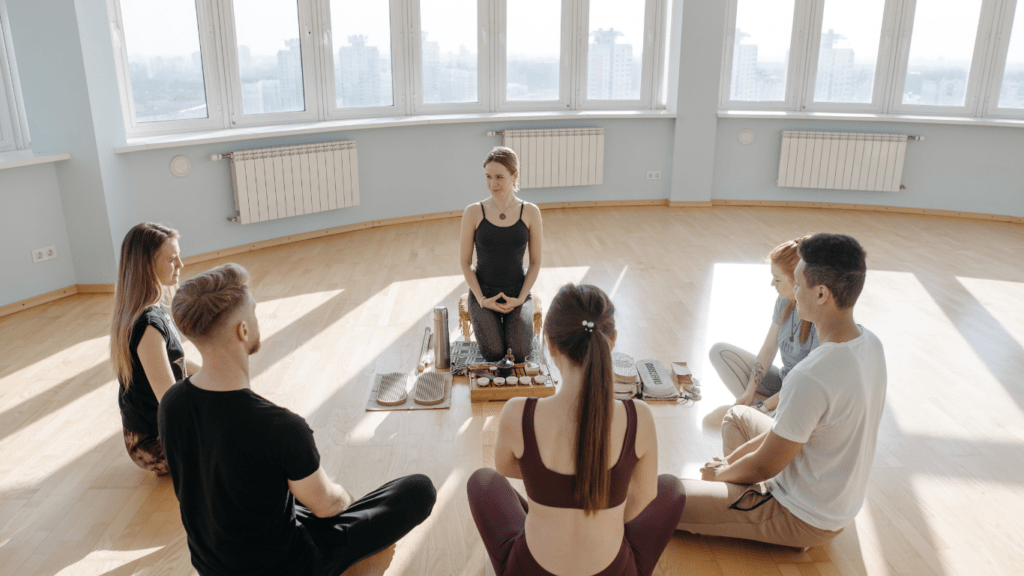 a group of people sitting on the floor in a yoga class