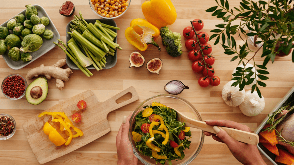 a person is holding a bowl of vegetables on a wooden table