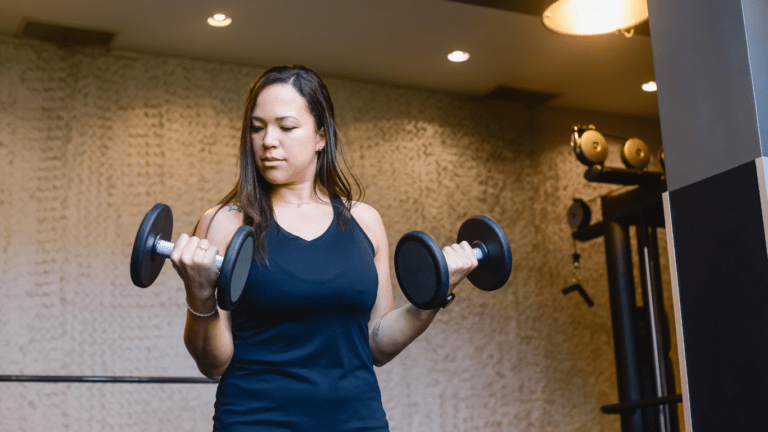 A person holding two dumbbells in a gym