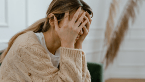 a person sitting at a table with their hands on their head