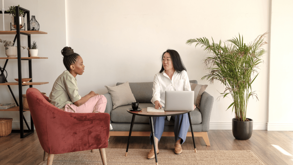 Two individuals sitting on a couch talking to each other