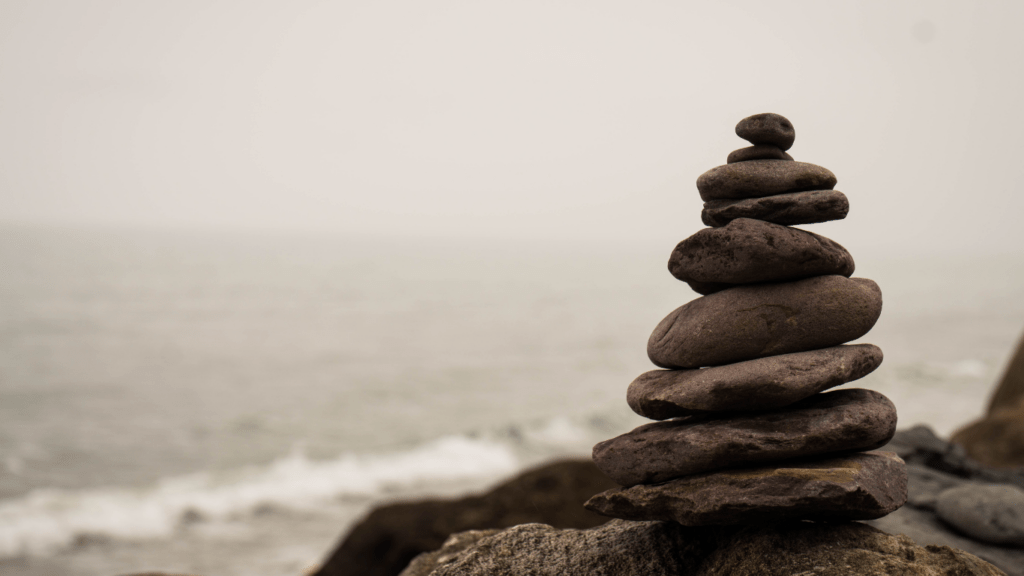 a stack of stones is sitting on top of a rock by the ocean