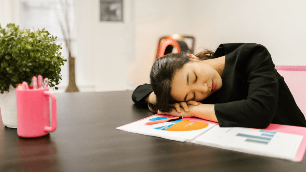 A person is sleeping on a desk in an office