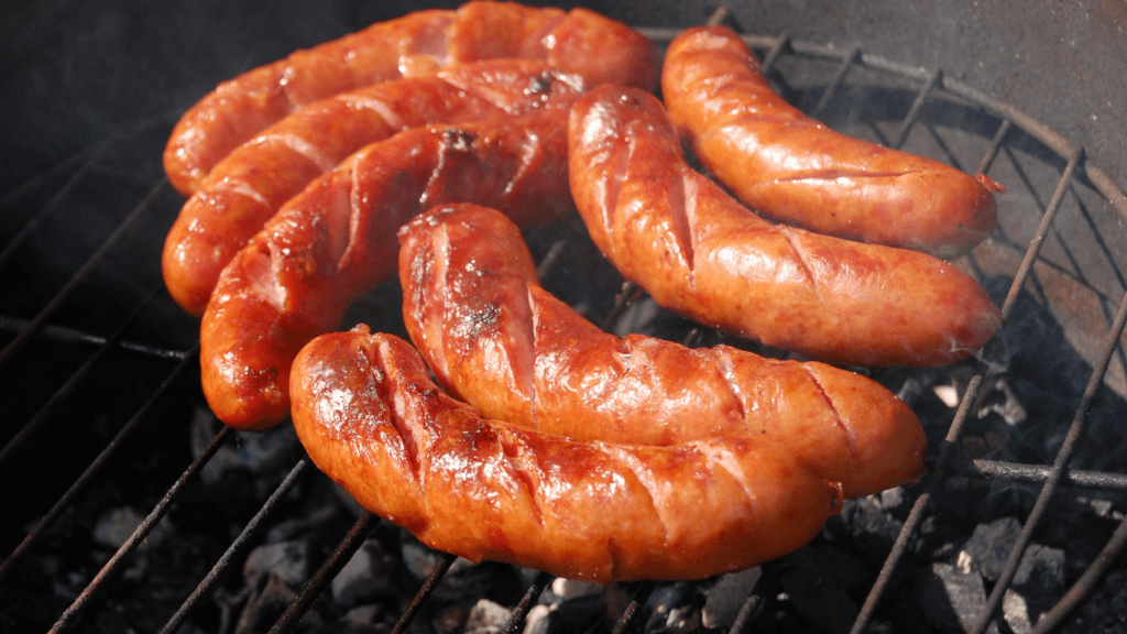 a group of sausages cooking on a grill