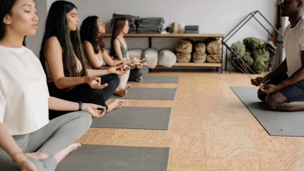 a group of people sitting on the floor in a yoga class