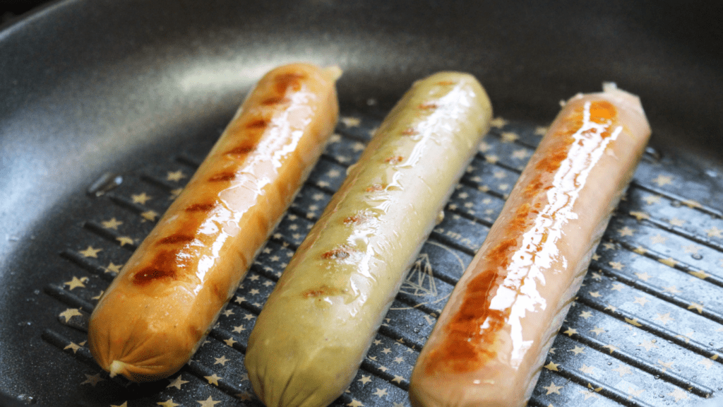 a group of sausages cooking on a grill