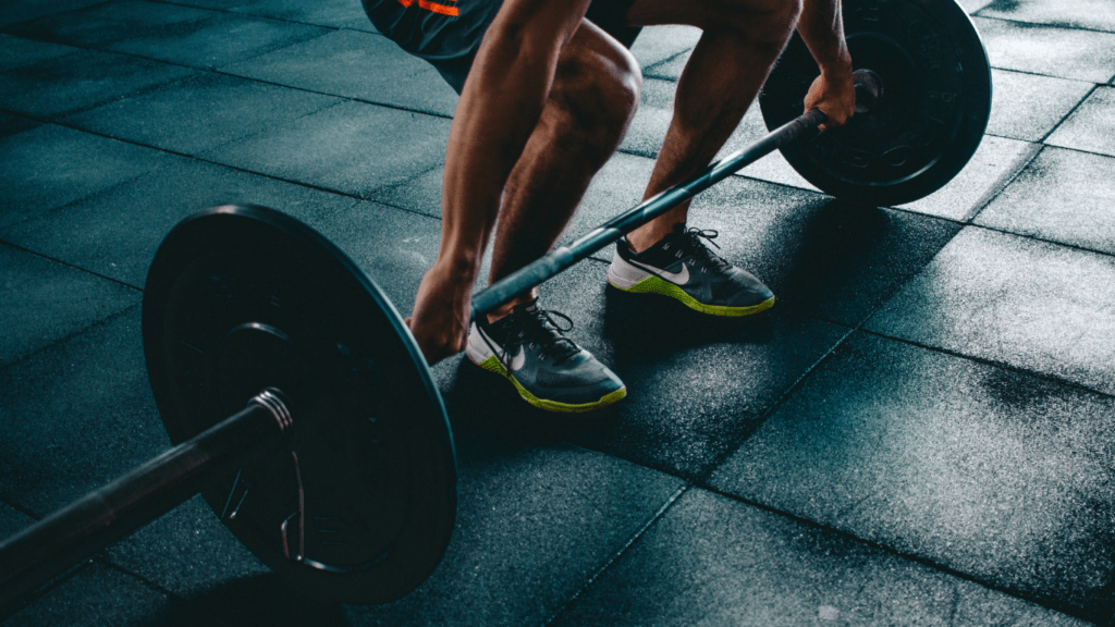 a person is lifting a barbell in a gym