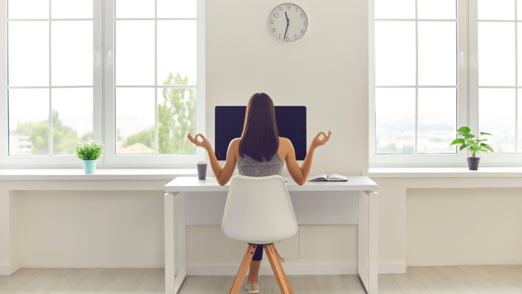 a person meditating on a yoga mat in front of a laptop