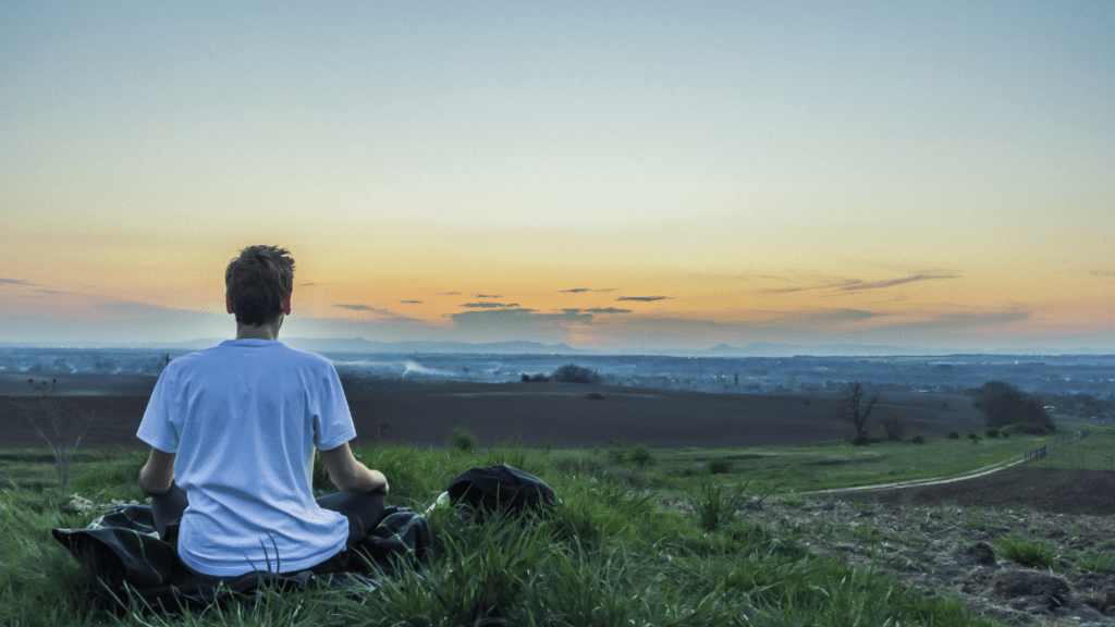 a person meditating on a yoga mat in front of the ocean